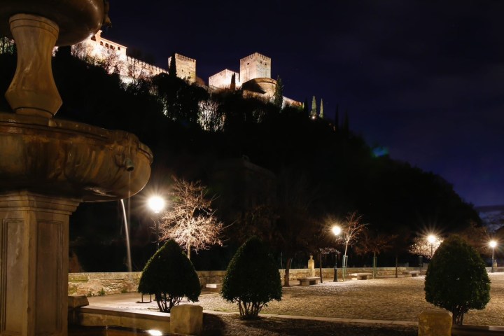 a fountain in front of a building lit up at night